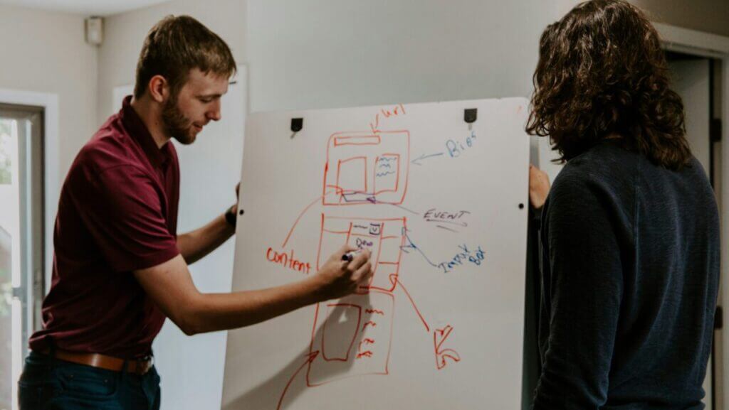 man drawing on dry-erase board